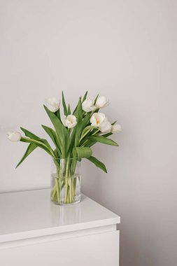 Beyaz bir masada cam vazoda beyaz laleler..