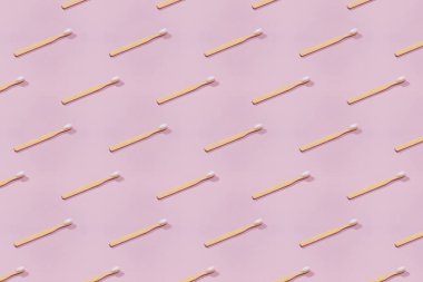 Pembe arka planda ahşap diş fırçası deseni.