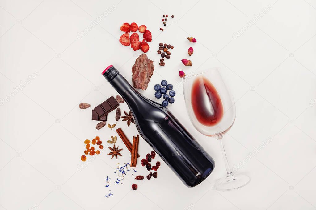 Composition with wine bottle, glass and possible flavor components of red wine