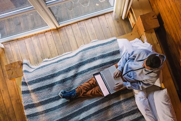 Uomo in abiti accoglienti che lavora sul computer portatile mentre seduto sul letto — Foto Stock