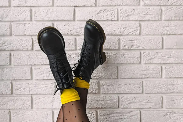 Vrouwen voeten in zwart lederen laarzen met polka dot panty en gele sokken — Stockfoto