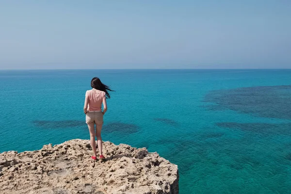 Młoda kobieta stojąca na klifie z pięknym widokiem t — Zdjęcie stockowe