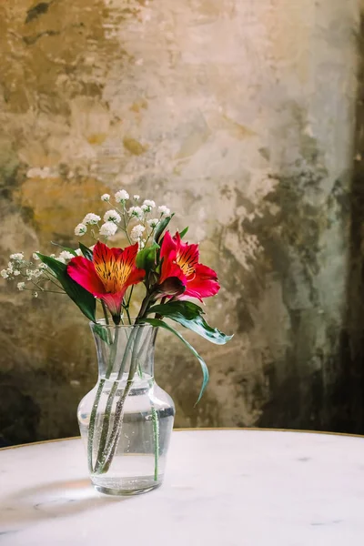 Kytice květin ve skleněné váze nad kamennou zdí — Stock fotografie