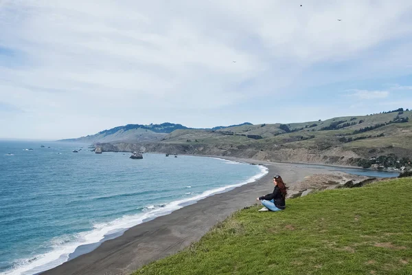 Woman sitting with a view to the ocean — Stock Photo, Image