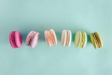 Pastel yeşil arka planda renkli tatlı kurabiyeleri.