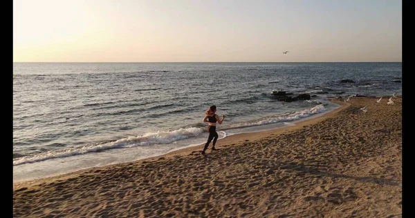 Tiro aéreo de uma jovem mulher correndo em uma praia — Fotografia de Stock