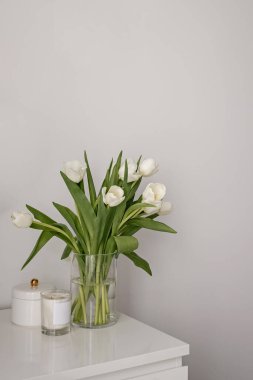 Beyaz bir masada cam vazoda beyaz laleler..