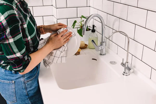 Unrecognizable woman washes dishes in the modern kitchen with white tiles. — Stock Photo, Image