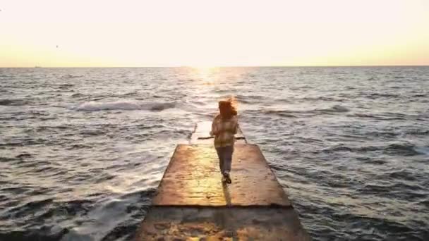 海の石の桟橋で新しい日に向かって実行している若い女性のスローモーションショット — ストック動画