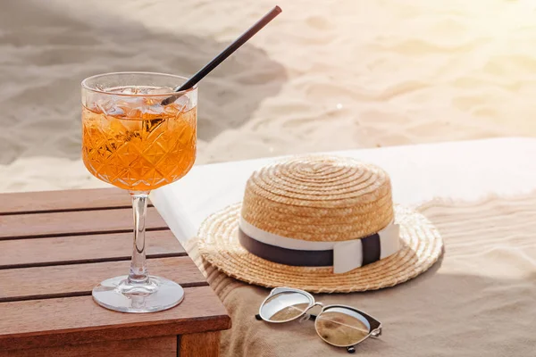 Szklanka aperolu Spritz, słomkowy kapelusz i okulary przeciwsłoneczne na plaży — Zdjęcie stockowe