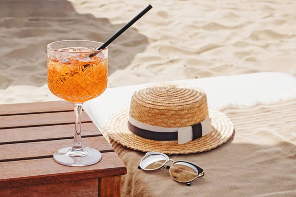 Un bicchiere di aperol Spritz, cappello di paglia e occhiali da sole sulla spiaggia — Foto Stock