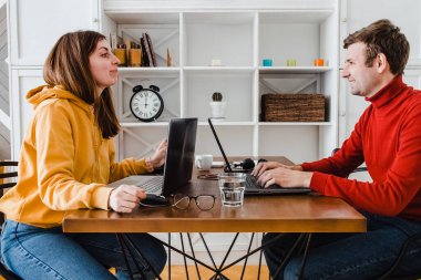 Kadın ve erkek aynı odada çalışırlar. Birbirlerine gülüyorlar.
