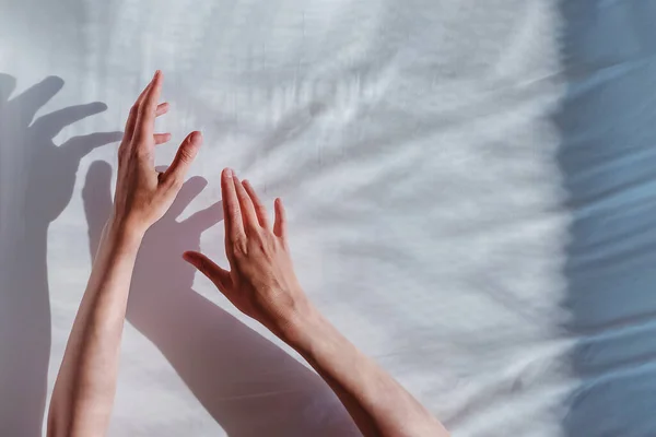Vrouwen hand reiken uit op witte doek achtergrond. — Stockfoto