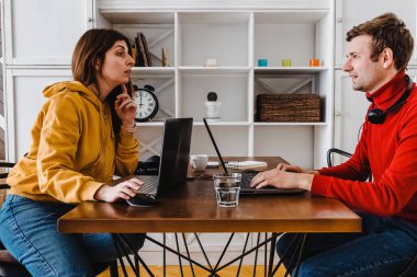 Kadın ve erkek birbirlerinin önündeki masada çalışıyor..