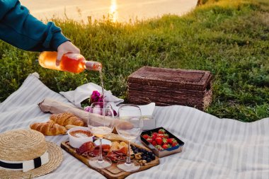 Kadınların elleri kadehe gül şarabı döker.