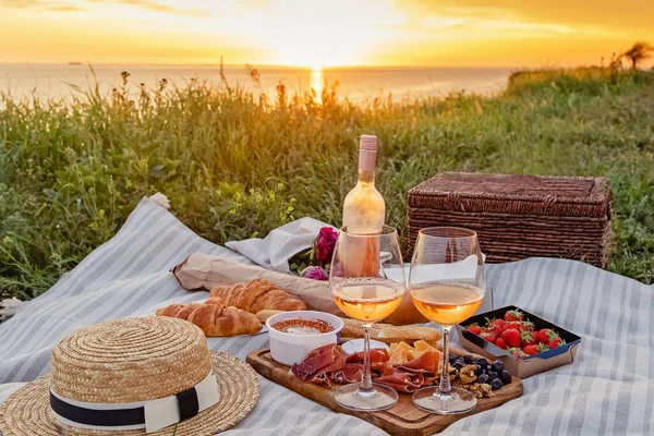 Picnic with strawberries, croissants and appetizers on the board and rose wine. — 图库照片