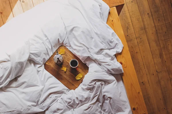 Bovenaanzicht van het koffiezetapparaat en kopje verse koffie op het comfortabele bed — Stockfoto