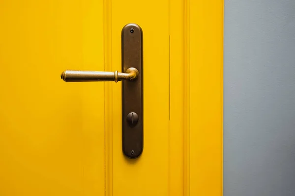 Porte jaune avec poignée de porte en bronze close-up. — Photo