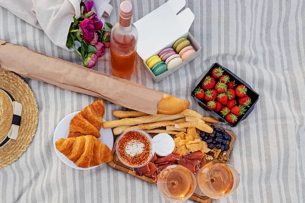 Picknick met aardbeien, croissants en hapjes op het bord en rozenwijn — Stockfoto