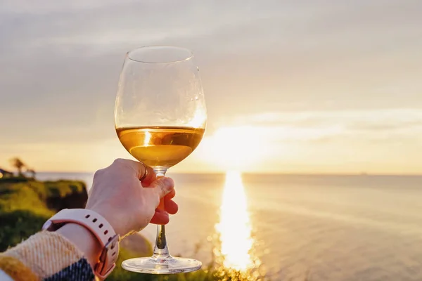 Mulher mão segurando um copo de vinho rosa ao pôr do sol — Fotografia de Stock