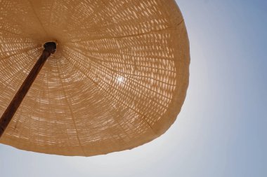 Hasır ve kumaştan büyük bir şemsiye.