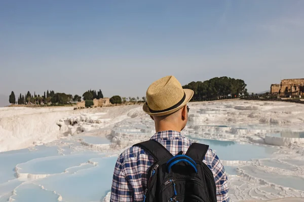 Fiatal férfi turista szalmakalapban nézi a természetes travertin medencék — Stock Fotó