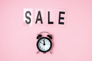 Pembe arka planda küçük çalar saat ve kelime satışı