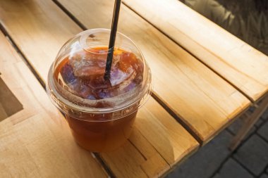 Take away coffee in plastic glass on wooden table