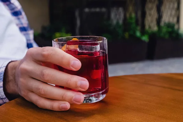 Крупним планом чоловіча рука тримає склянку алкогольного коктейлю — стокове фото