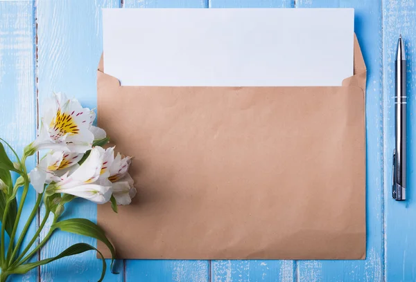 Blank paper in the envelope, pen and alstroemeria flowers — Stock Photo, Image