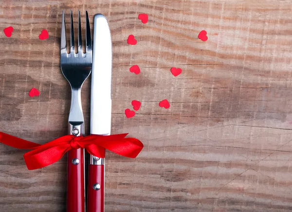 Kniv och gaffel och lilla röda hjärtan på trä bordet. — Stockfoto