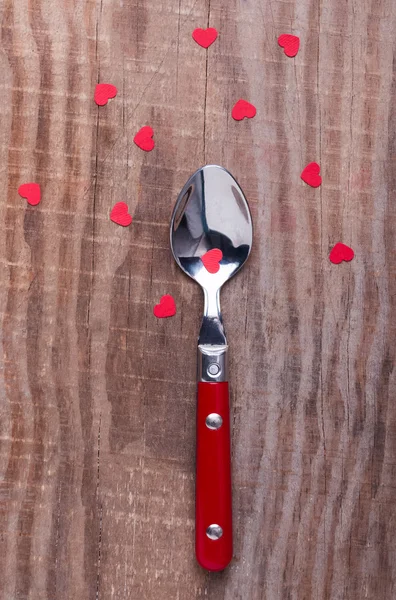 Little red paper hearts and a spoon on the wooden table. — Stock Photo, Image