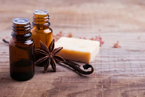 Bottles with aroma oil, vanilla pods and hand made soap — Stock Photo, Image