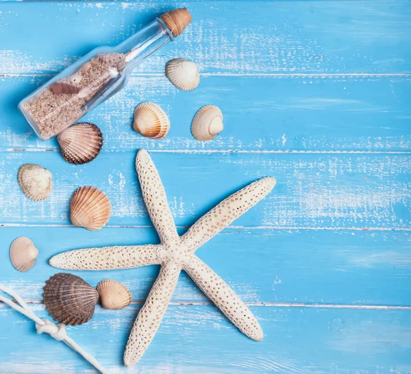 Muszle, rozgwiazdy i butelki z piasku na niebieski tyłu drewniane — Zdjęcie stockowe