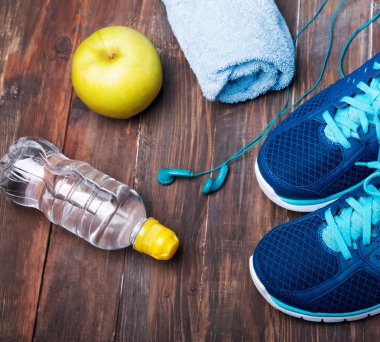 Spor ayakkabı, su, havlu, kulaklık ve ahşap backgr elma