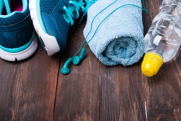 Sneakers, water, handdoek en oortelefoons op houten achtergrond — Stockfoto