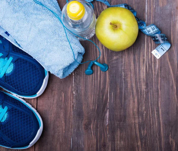 Neakers, water, towel and earphones on the wooden background — Stock Photo, Image