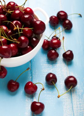 Kiraz bir kase mavi ahşap arka plan üzerinde kapat