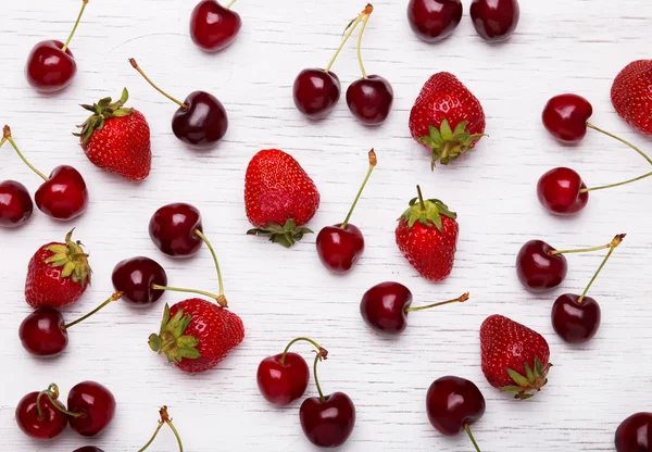 Frische Kirschen und Erdbeeren auf dem weißen Holztisch — Stockfoto