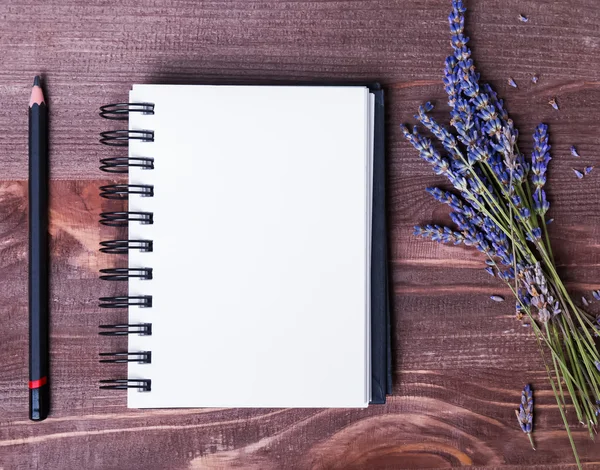 Lavender flowers, empty notepad and pensil on wooden table — Stock Photo, Image