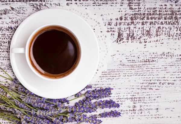 Xícara de café e flores de lavanda na mesa de madeira branca — Fotografia de Stock