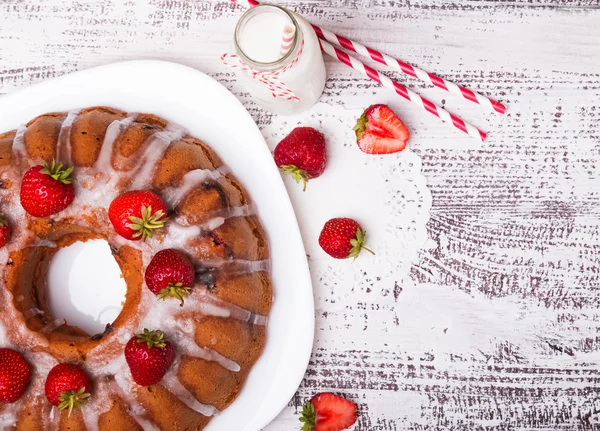 Leckerer glasierter Kuchen mit Erdbeeren auf weißem Holztisch — Stockfoto