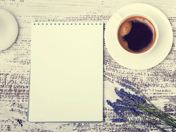 Blocco note vuoto, tazza di caffè e fiori di lavanda su legno bianco — Foto Stock