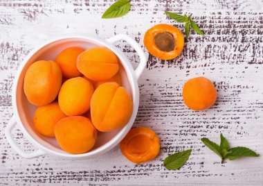 Beyaz renkli tablo üzerinde bir kapta taze kayısı.