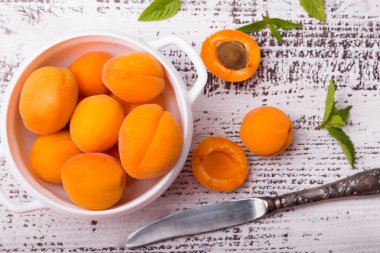 Beyaz renkli ahşap masa üzerinde bir kasede kayısı