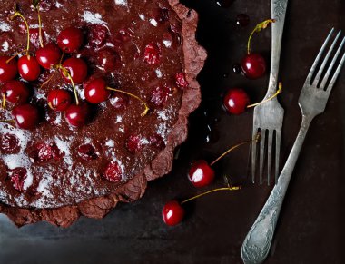 Ganache ve kiraz ile Çikolatalı tart. Karanlık tarzı fotoğraf.