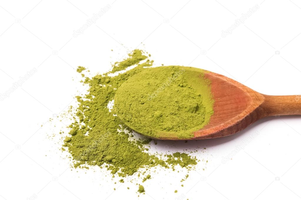Matcha tea in a wooden spoon on white background