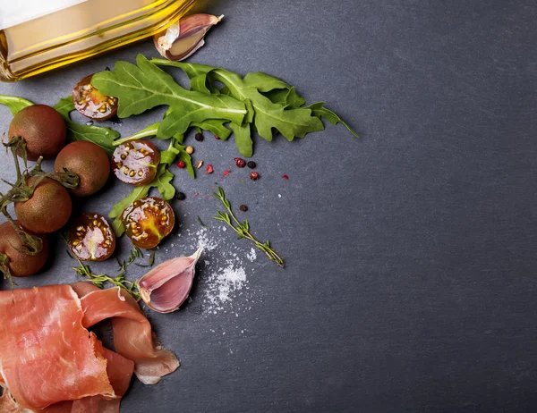 Kiraz domates, jambon, roka ve baharat kara tahta üzerinde