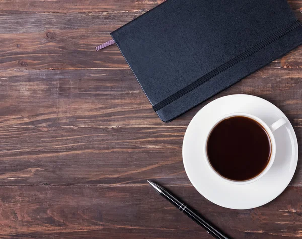Bloc de notas, pluma y taza de café negro en la mesa de madera —  Fotos de Stock