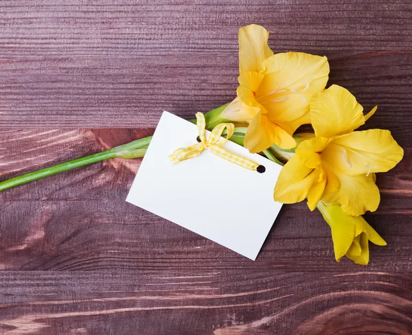 Güzel sarı çiçek ve te ahşap masa üzerinde boş oyun kağıdı — Stok fotoğraf